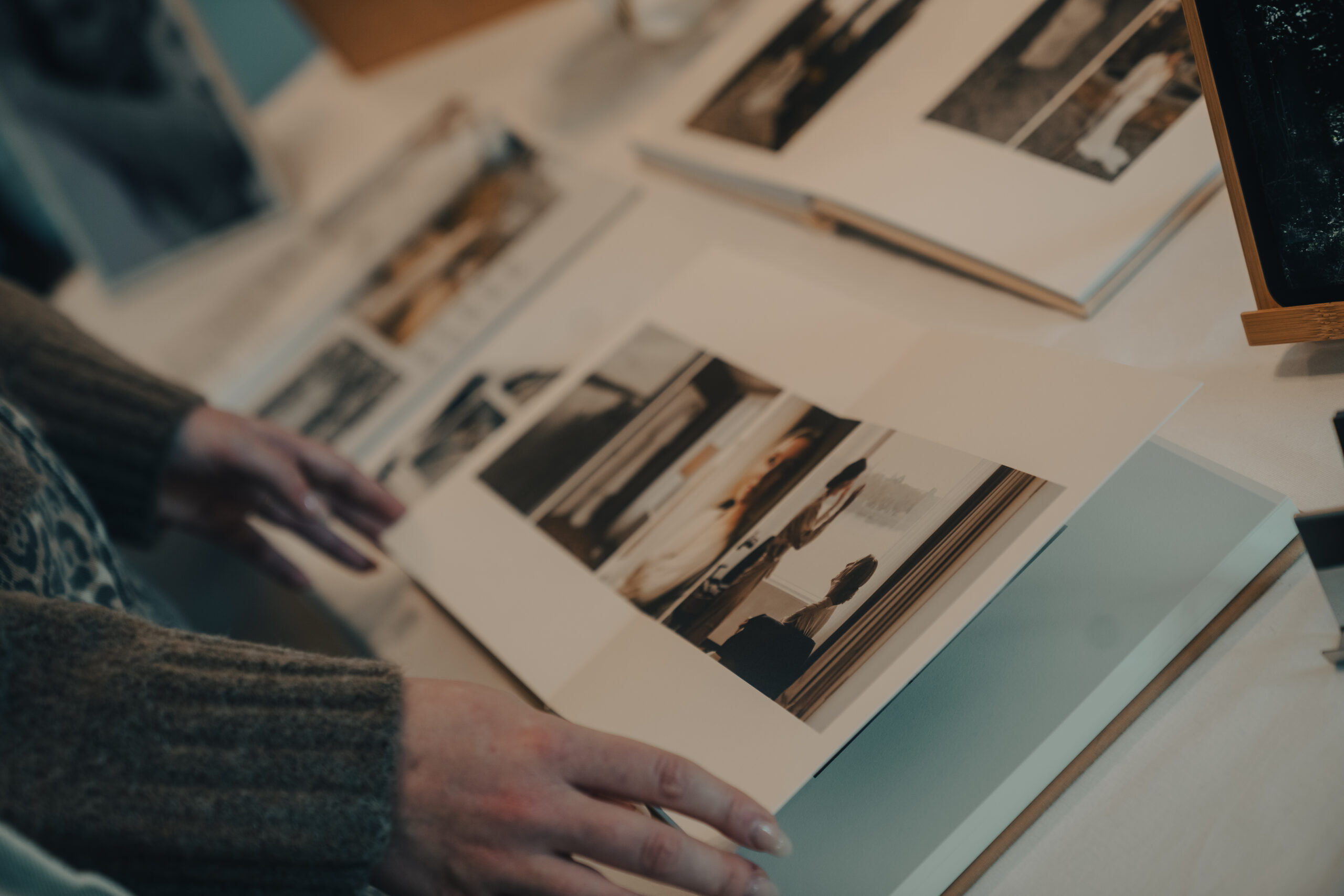 Die Hände einer Frau, die sich gerade Hochzeitsalben mit Fotos anschaut.